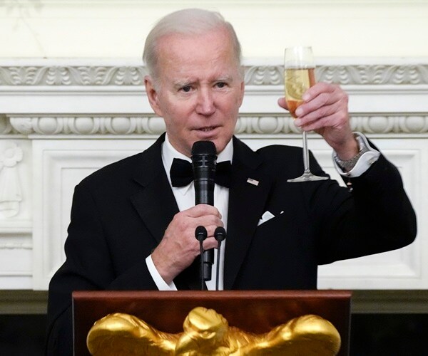 Joe Biden toasts while speaking into a microphone