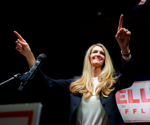 kwlly loefller raises hands in the air