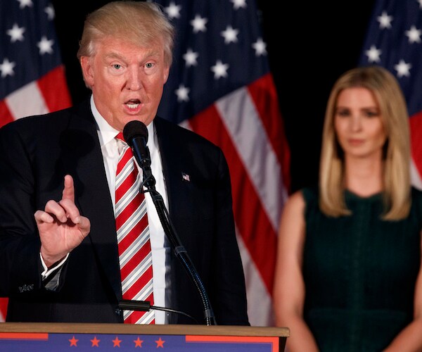 president donald trump points with his right index finger during a rally while daughter ivanka trump looks on
