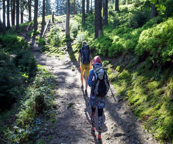 A man and a woman hiking on a trail in the woods