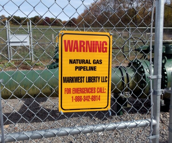 warning sign for a natural gas pipeline outside a gate is shown