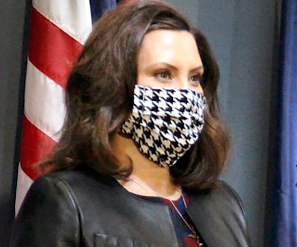 michigan gov. gretchen whitmer addresses the media with a black and white checkered face mask
