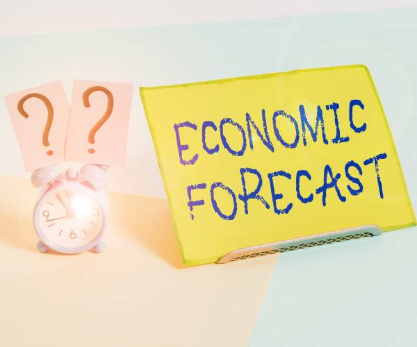 a clock next to a piece of paper reading economic forecast
