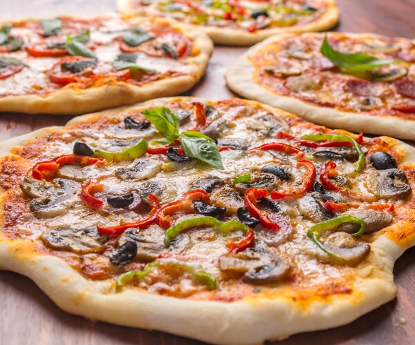 4 pizzas sitting on a wooden table