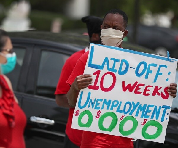 a man holds up a sign in protest to the faulty unemployment system in florida