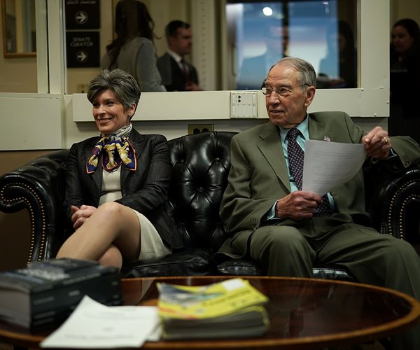 Joni Ernst and Chuck Grassley sit on a couch