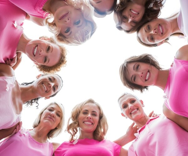 women in circle wearing pink shirts to support breast cancer