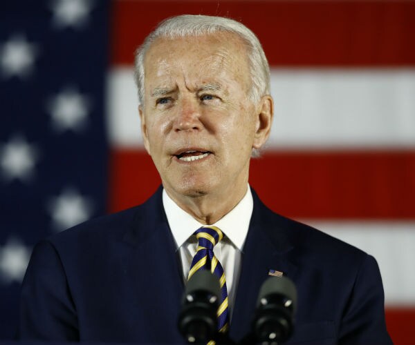joe biden is seen speaking at a podium with the us flag in the background