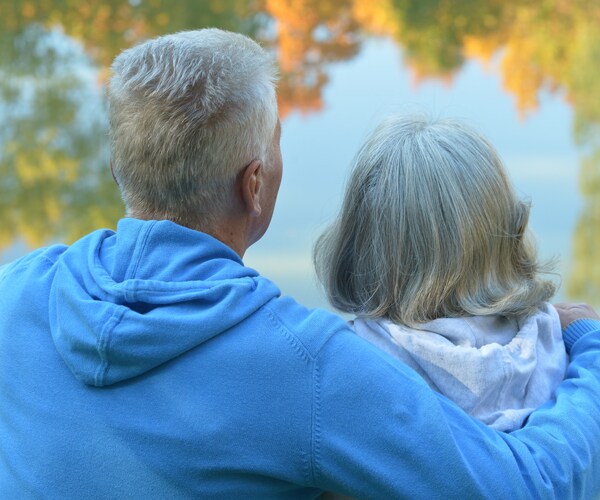 a senior couple sitting and looking at the water outside
