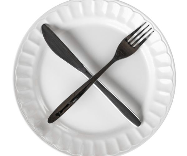 a crossed knife and fork on empty plate symbolizing fasting
