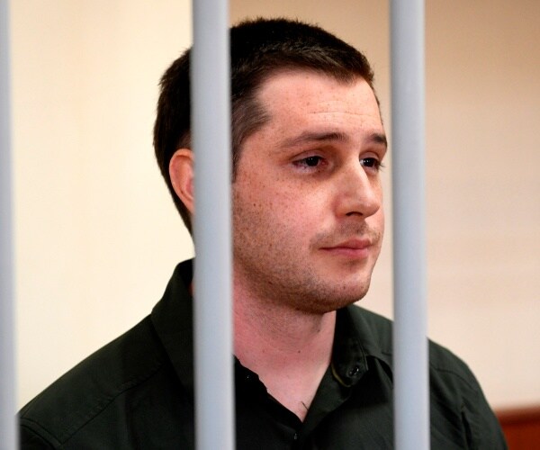 Trevor Reed stands inside a defendants' cage