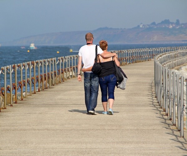 couple walking with arms around each other on a pier
