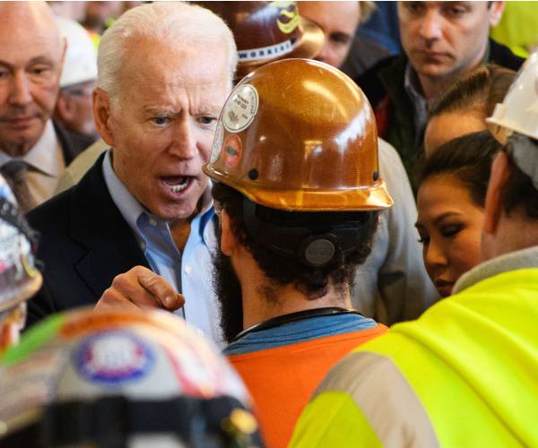 biden points his finger and yells at a man wearing a hard hat and yellow protective vest