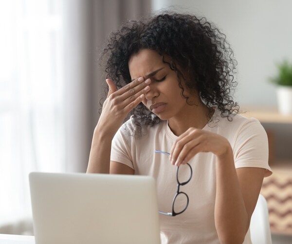 a woman rubbing her eyes and suffering from eye strain