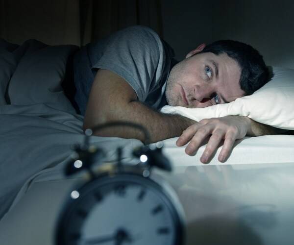 man in bed at night with eyes wide open, unable to sleep