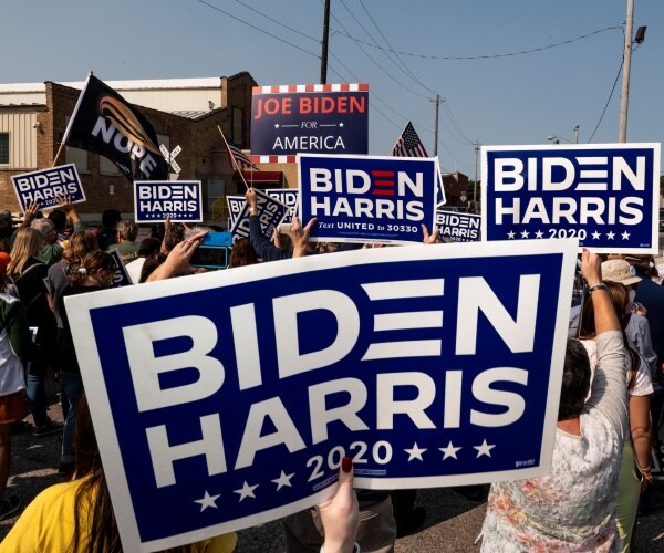 supporters hold up biden harris signs outside