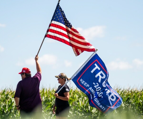 trump supporters wave flags in a wisconsin field