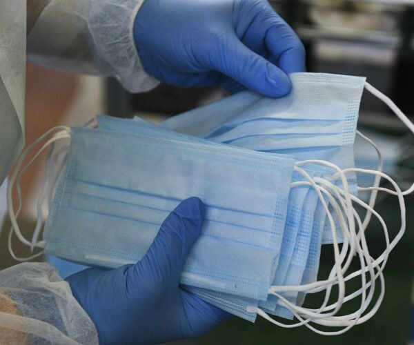 a medical worker holds a handful of blue medical vests