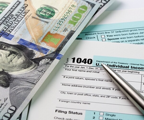 irs tax form and one hundred dollar bill and pen