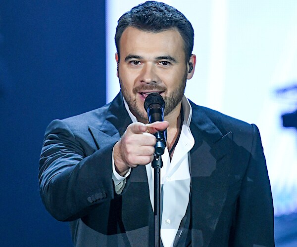 azerbaijani singer emin agalarov sings into a mic while pointing forward with his right index finger