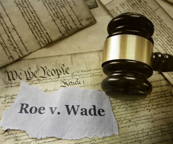 the constitution with a judge gavel and a piece of paper with roe v wade written on it