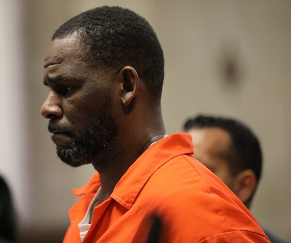 r kelly stands in courtroom in orange jumpsuit