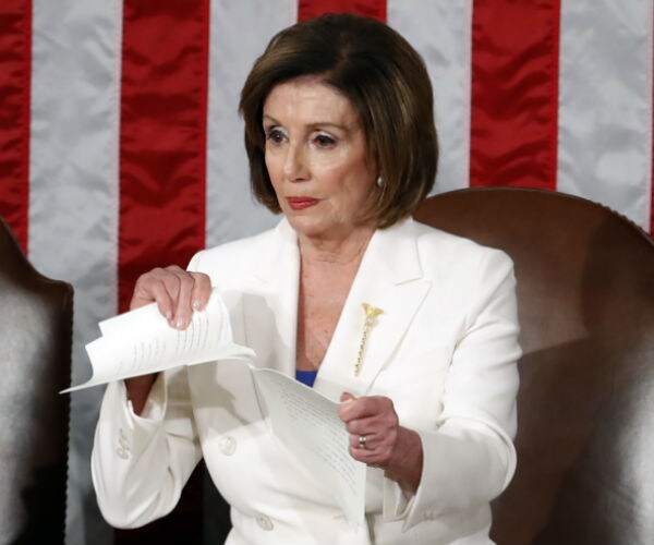 House Speaker Nancy Pelosi, dresses in white, tears her copy of President Donald Trump's State of the Union 