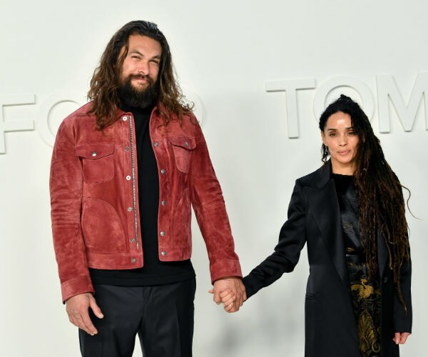 Jason Momoa and Lisa Bonet are seen. momoa is rust jacket and all black attire, bonet in all black and gold attire