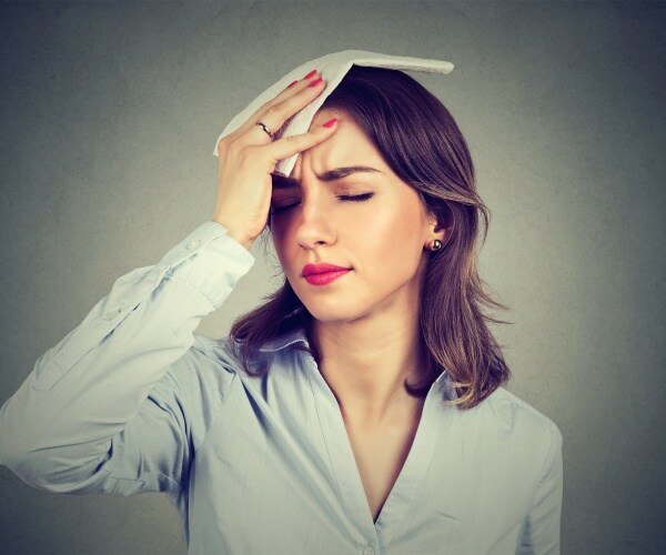 woman with hot flash, putting cold compress on her forehead