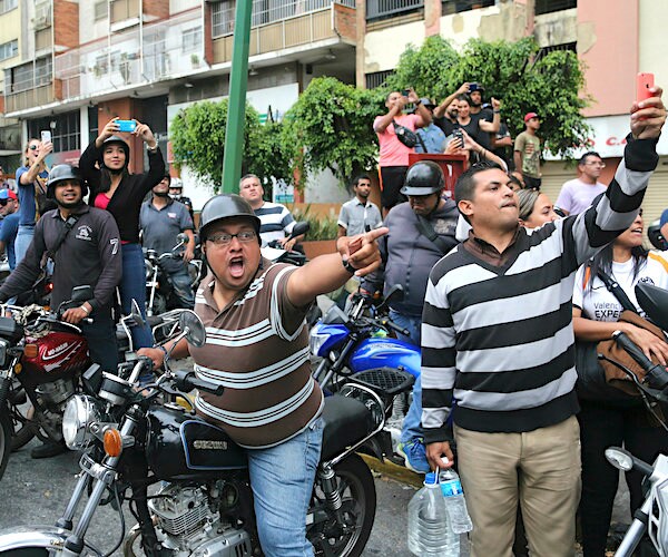 a gathering in venezuela features country people pointing and taking pictures of chaos