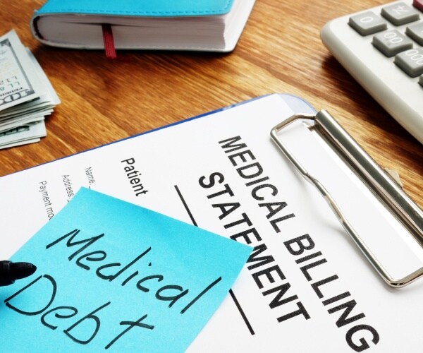 Medical billing statement, post-it that says 'medical debt', cash, calculator