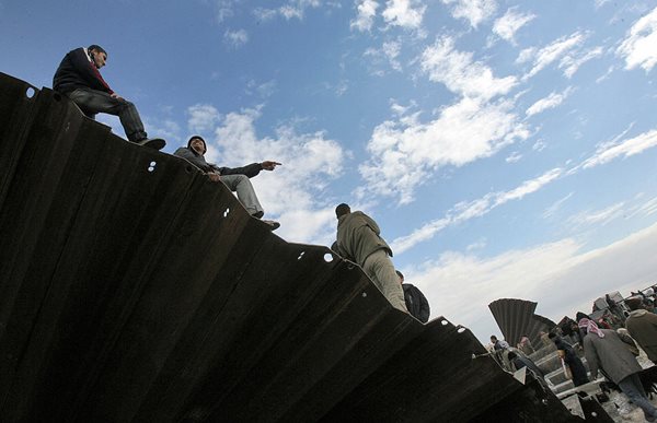 palestinians sitting on breached gaza wall