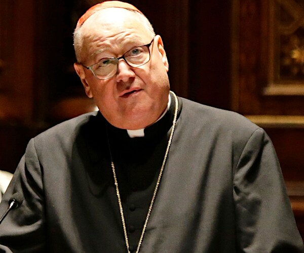 Cardinal Timothy Dolan tilts his head to the right and looks up