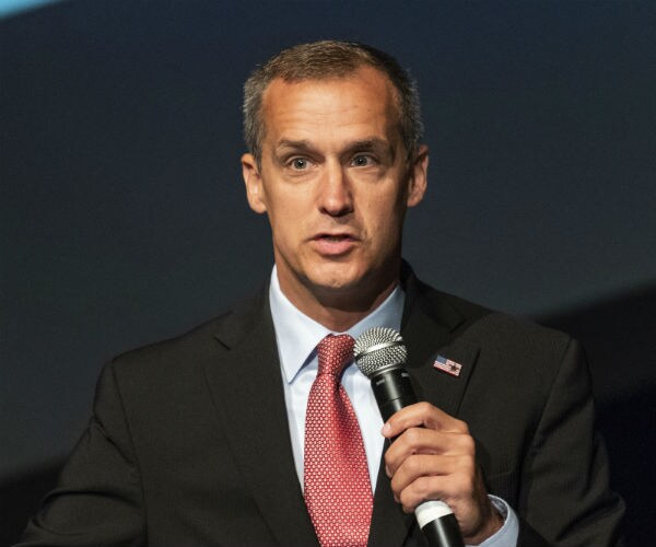 corey lewandowski is shown in suit, red tie and white dress shirt