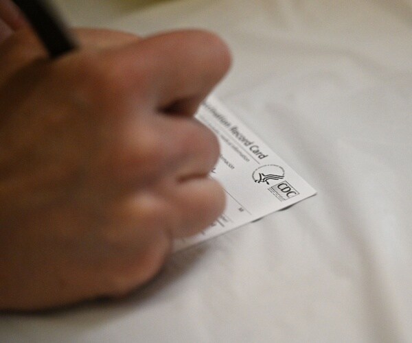 hand filling out a CDC vaccine card
