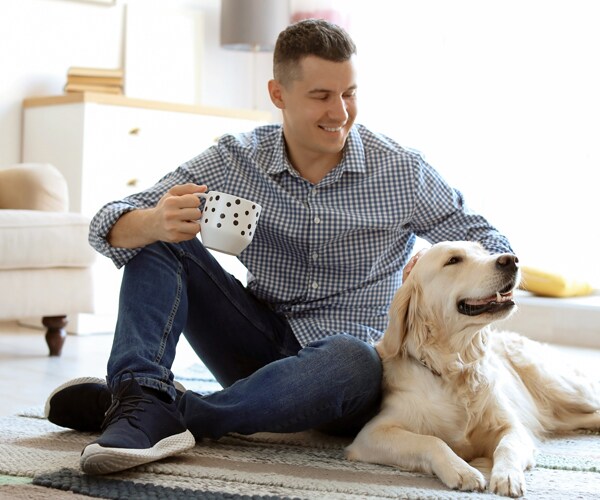 a man sitting on the floor next to his dog