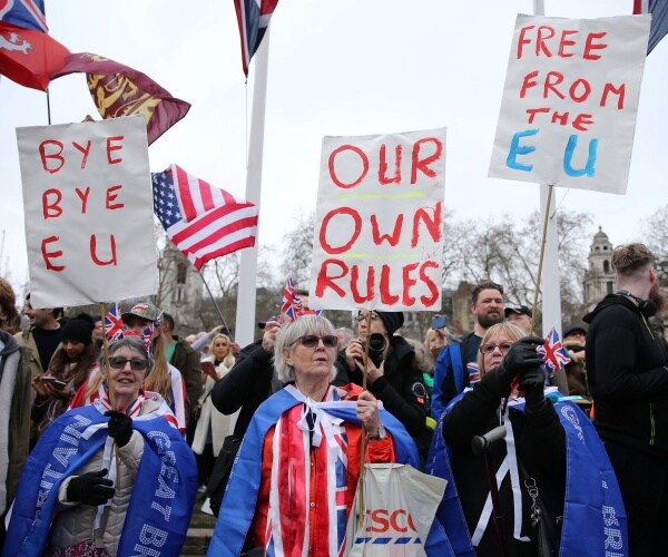 brexit supporters with signs saying "bye bye eu" and "our own rules"