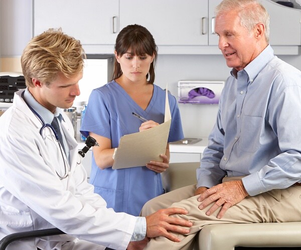 doctor examines mans knee while nurse looks on