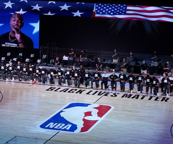 players kneel in front of the nba logo before a game.