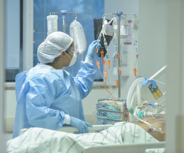nurse in brazil wearing a blue protective suit and white cap treating a patient