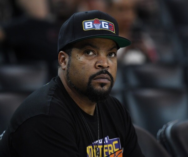 ice cube wears a baseball hat and sits in a stadium