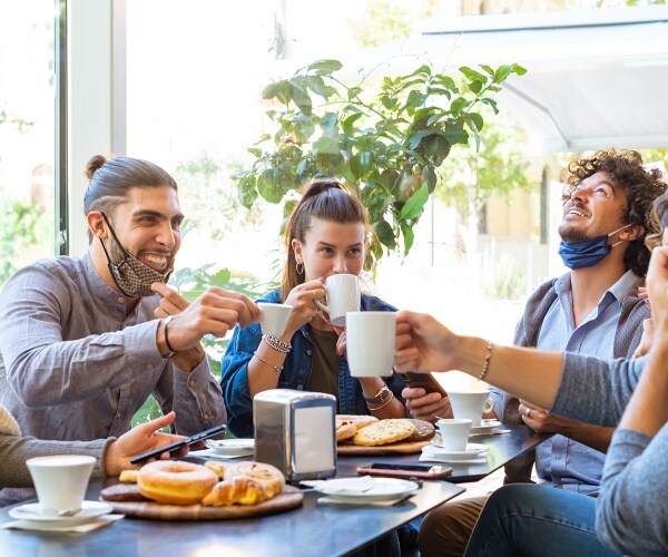 adults drinking coffee while semi wearing masks