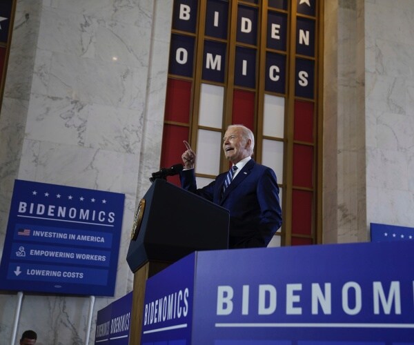 joe biden pointing while surrounded by bidenomics signs