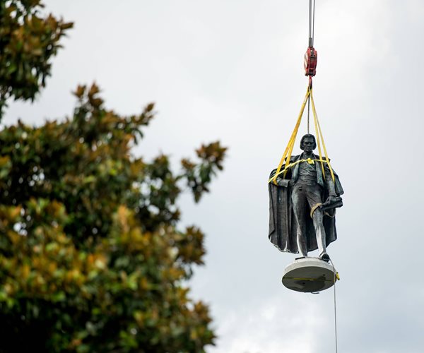 statue in rigging against the sky with a treetop beside it