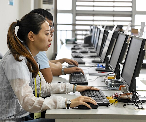 chinese students sit at computer terminals at a long table