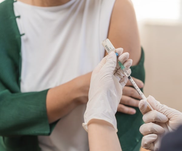 woman about to get a COVID vaccine in her left arm