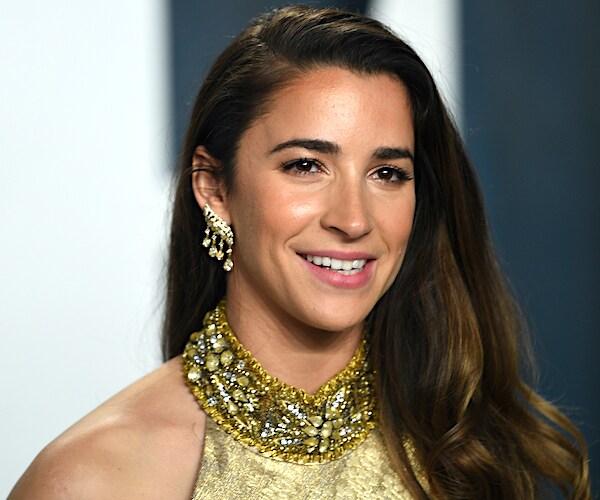 aly raisman smiles dressed in gold at the oscars