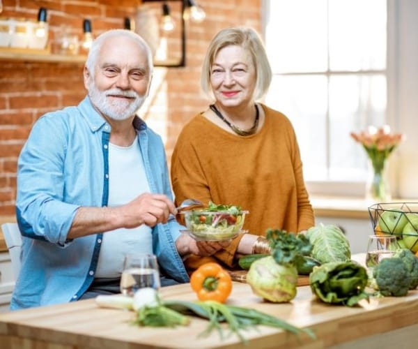 older couple in kitchen preparing healthy food