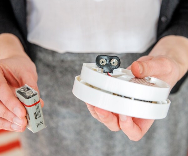 woman changing battery in smoke detector