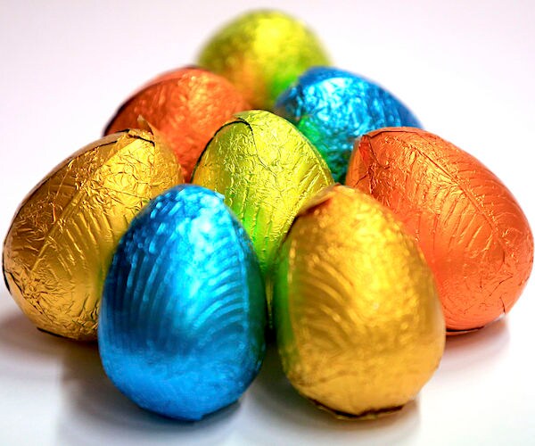 foil covered chocolate easter eggs are stacked next to each other on a white table